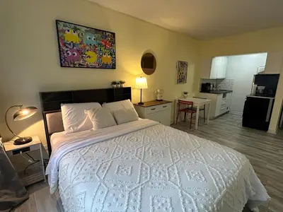 a bedroom with a large white bed and a kitchen at studio in heart of DT, 2 metros, Concordia in Montréal