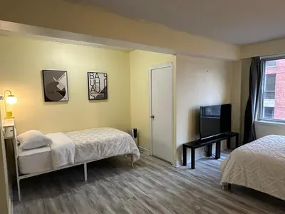 a room with two beds and a desk and a window at studio in heart of DT, 2 metros, Concordia in Montréal