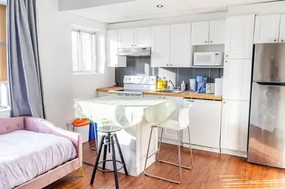 a kitchen with white cabinets and a table and chairs at 1 BDR at heart of DT, walk to 2 metros, Concordia in Montréal