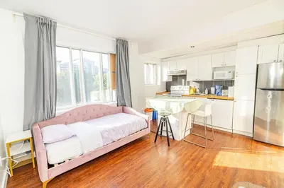 a bedroom with a pink bed and a kitchen at 1 BDR at heart of DT, walk to 2 metros, Concordia in Montréal