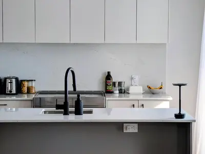 a kitchen with white cabinets and a sink at Old Montreal Suite with Rooftop Pool & Terrace in Montréal