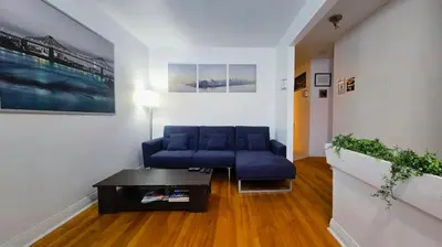 a living room with a blue couch and a table at Private rooms in shared appartment in Montréal