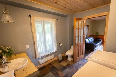 a bathroom with a sink and a toilet and a couch at Camping de la Rivière Nicolet in Wotton