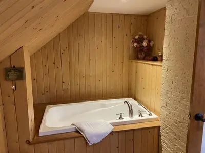 a bath tub in a wood paneled bathroom at Camping de la Rivière Nicolet in Wotton