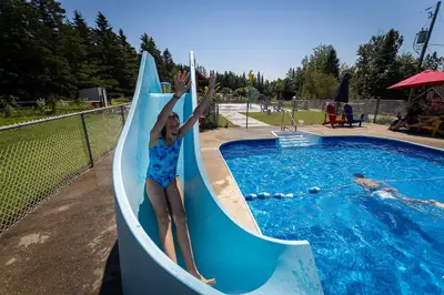 a young girl is riding on a water slide at Camping de la Rivière Nicolet in Wotton