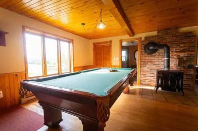 a pool table in a room with a fireplace at Camping de la Rivière Nicolet in Wotton