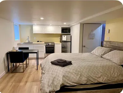a bedroom with a bed and a table and a kitchen at Studio moderne et tranquille in Montréal