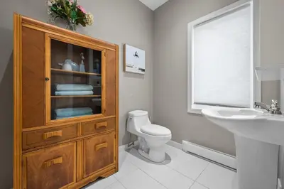 a bathroom with a sink and a toilet and a wooden cabinet at A Getaway on Lake Champlain in Venise-en-Québec