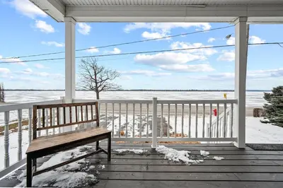 a bench on a porch with a view of the ocean at A Getaway on Lake Champlain in Venise-en-Québec