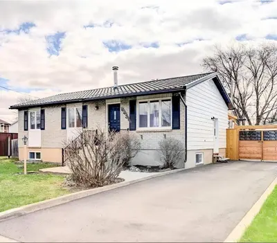a white house with blue windows and a driveway at Family-Friendly Spacious 2BR Cozy Basement Suite - Near Attractions - Sleepsn5 in Longueuil