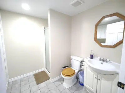 a bathroom with a toilet and a sink and a mirror at Family-Friendly Spacious 2BR Cozy Basement Suite - Near Attractions - Sleepsn5 in Longueuil