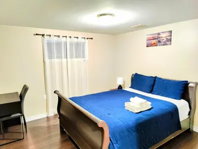 a bedroom with a bed with blue sheets and a chair at Family-Friendly Spacious 2BR Cozy Basement Suite - Near Attractions - Sleepsn5 in Longueuil