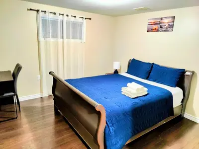 a bedroom with a large bed with blue sheets at Family-Friendly Spacious 2BR Cozy Basement Suite - Near Attractions - Sleepsn5 in Longueuil