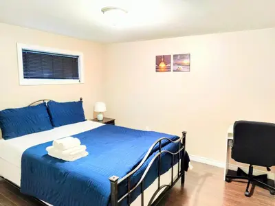 a bedroom with a blue bed and a chair at Family-Friendly Spacious 2BR Cozy Basement Suite - Near Attractions - Sleepsn5 in Longueuil