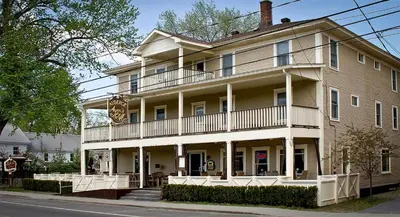 a large building with a balcony on a street at Auberge Ayer's Cliff in Ayer's Cliff