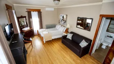 a living room with a couch and a tv at Auberge Ayer's Cliff in Ayer's Cliff