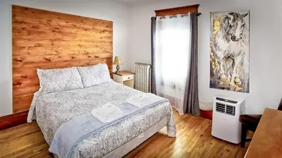 a bedroom with a bed and a wooden wall at Auberge Ayer's Cliff in Ayer's Cliff