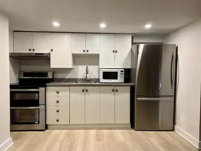 a kitchen with white cabinets and a stainless steel refrigerator at Appartement privé et calme in Montréal