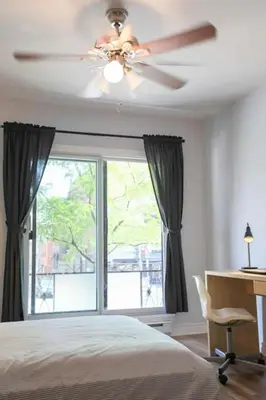 a bedroom with a ceiling fan and a desk and a window at St-denis II-3 Apt In the heart of Montreal in Montréal