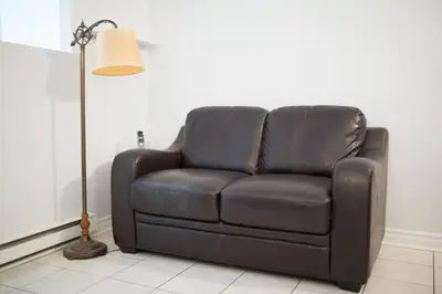 a brown leather couch in a living room with a lamp at St-denis II-3 Apt In the heart of Montreal in Montréal