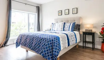 a bedroom with a blue and white bed with a window at Le Mont-Royal Lounge by HomeInMontreal in Montréal