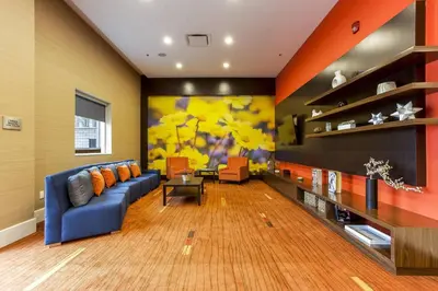 a living room with a blue couch and orange walls at Courtyard by Marriott Montreal West Island/Baie D’Urfe in Baie-dʼUrfé