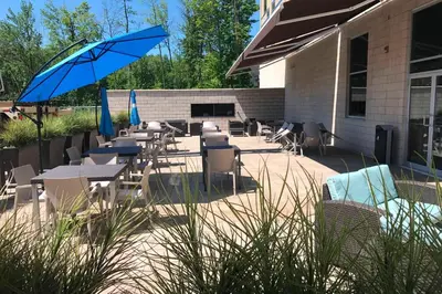 a patio with tables and chairs and an umbrella at Courtyard by Marriott Montreal West Island/Baie D’Urfe in Baie-dʼUrfé