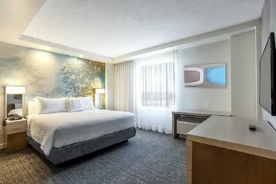 a hotel room with a bed and a television at Courtyard by Marriott Montreal West Island/Baie D’Urfe in Baie-dʼUrfé