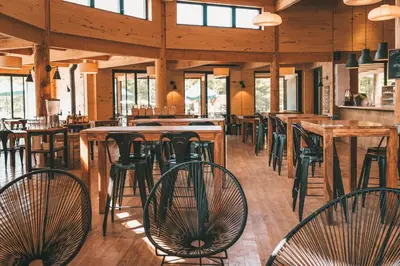 a restaurant with tables and chairs in a building at Huttopia Sutton in Sutton