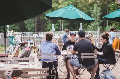 a group of people sitting at tables under an umbrella at Huttopia Sutton in Sutton
