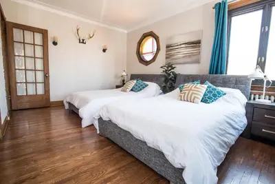 two beds in a bedroom with blue curtains at MTLVacationrentals-The MTLVR Kisses in Montréal