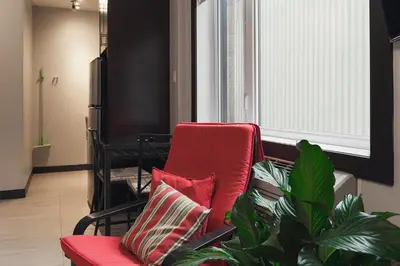 a red chair with two pillows next to a plant at Cjour Apartments in Montréal