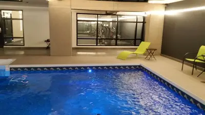 a large swimming pool in a building with green chairs at Grand Times Hotel Drummondville in Drummondville