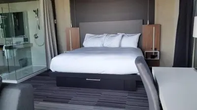a bedroom with a bed and a glass shower at Grand Times Hotel Drummondville in Drummondville