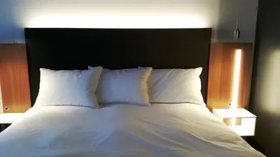 a large bed with white pillows and a black headboard at Grand Times Hotel Drummondville in Drummondville