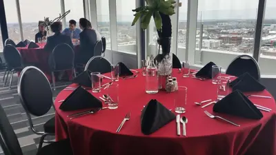 a table with a red table cloth and a vase of flowers on it at Grand Times Hotel Drummondville in Drummondville