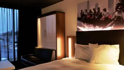 a bedroom with a bed and a chair and a picture at Grand Times Hotel Drummondville in Drummondville