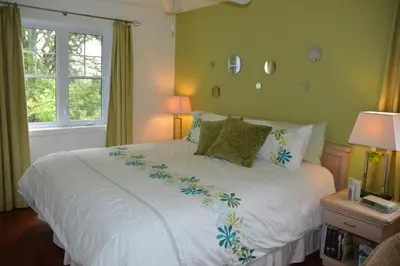 a bedroom with a bed with white sheets and a window at Lecomte De La Fontaine in North Hatley