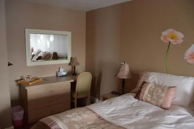 a bedroom with a bed and a desk with a flower on the wall at Lecomte De La Fontaine in North Hatley