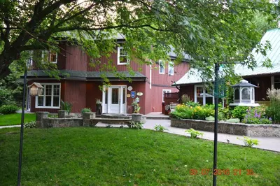 a red house with a bench in the yard at Lecomte De La Fontaine in North Hatley