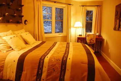 a bedroom with a large bed and two windows at Lecomte De La Fontaine in North Hatley