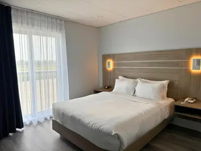 a bedroom with a large bed and a large window at La Porte de la Mauricie in Louiseville