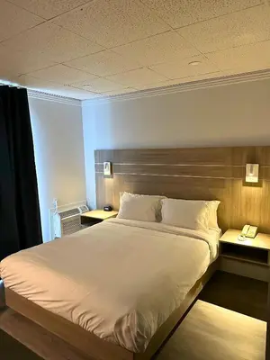 a bedroom with a large white bed with two tables at La Porte de la Mauricie in Louiseville
