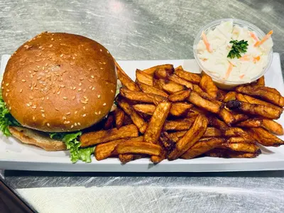 a plate with a hamburger and french fries and coleslaw at La Porte de la Mauricie in Louiseville
