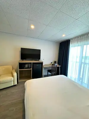 a hotel room with a bed and a flat screen tv at La Porte de la Mauricie in Louiseville