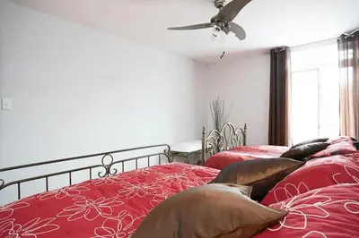 a bedroom with two beds with red sheets and a ceiling fan at Big Cozy House in Montréal