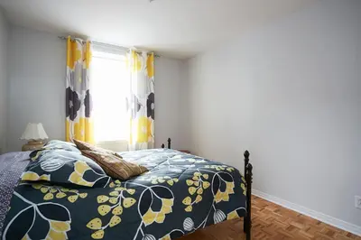 a bedroom with a bed and a window with yellow curtains at Big Cozy House in Montréal