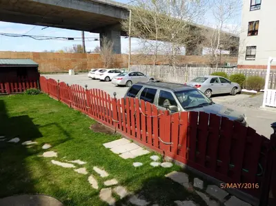 a red fence with a car parked in a parking lot at Big Cozy House in Montréal
