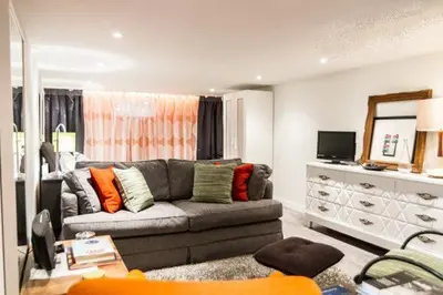 a living room with a gray couch and a mirror at L'Adresse Botanique - Studio in Montréal
