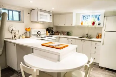 a kitchen with white cabinets and a white refrigerator at L'Adresse Botanique - Studio in Montréal